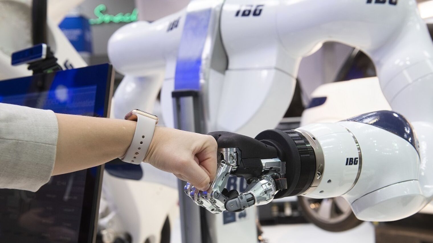 Menschliche Hand trifft auf Roboterhand mit der Faust.