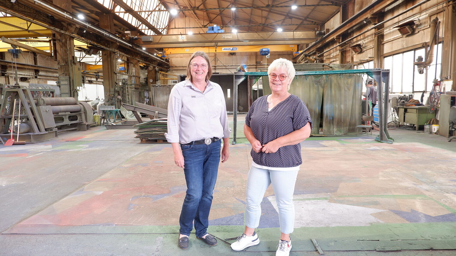 STICHWEH-Geschäftsführerin Anja Gröhlich und Ute Olthoff, Mitarbeiterin Administration, stehen in der großen Werkstatthalle.