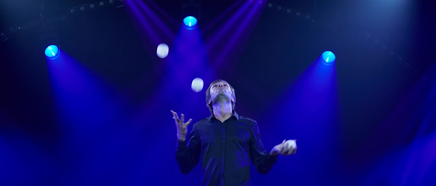 Jongleur Pavel Roujilo jongliert mit kleinen weißen Bällen.