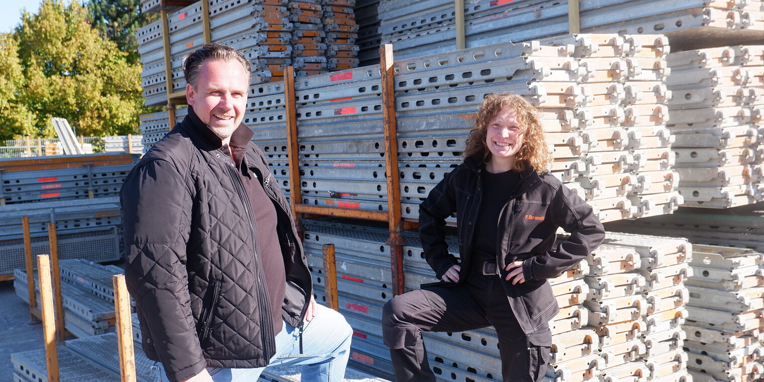 Ausbilder und Auszubildende stehen draußen vor einem 