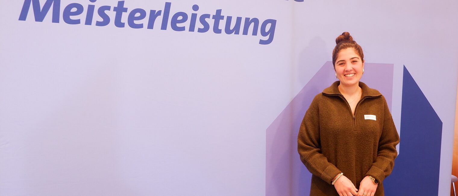 Zarah Javid Milani vor der Leinwand mit der Aufschrift "Ehrenamt ist eine Meisterleistung".