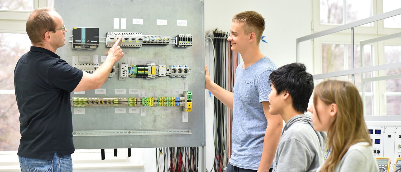 Jugendliche und Lehrer in der Berufsausbildung für Elektrotechnik.