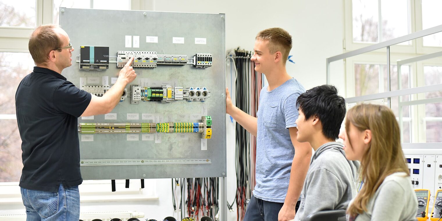 Jugendliche und Lehrer in der Berufsausbildung für Elektrotechnik.