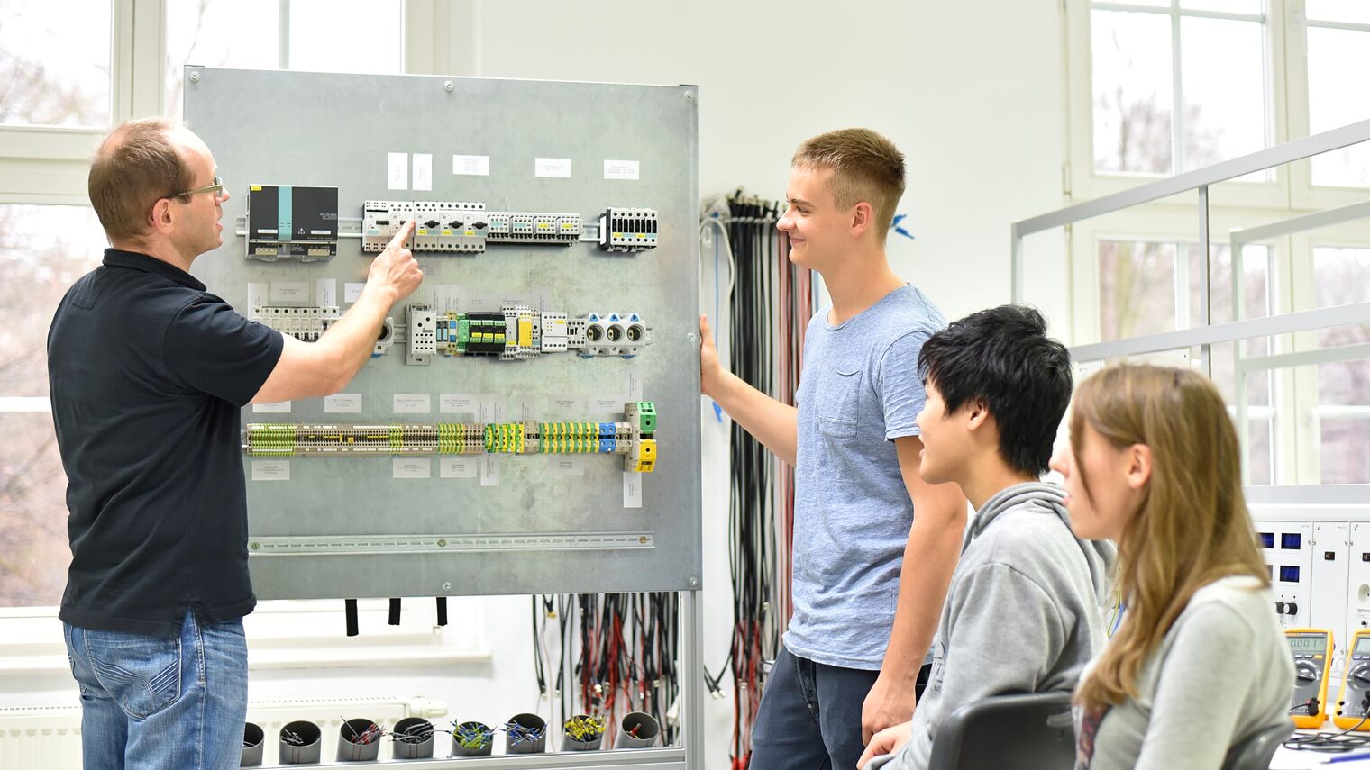 Jugendliche und Lehrer in der Berufsausbildung für Elektrotechnik.