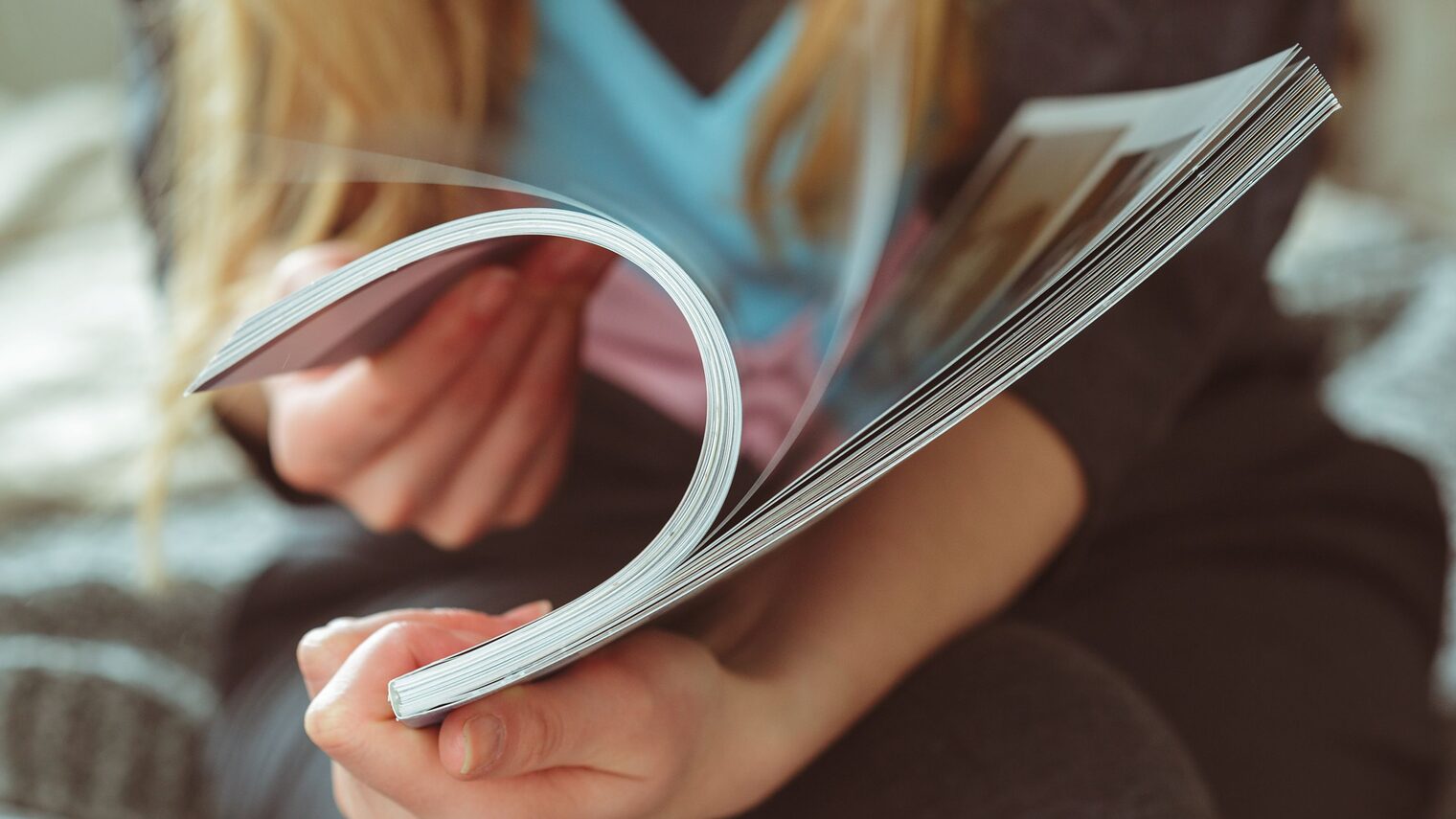 Hände einer Frau, die durch ein Magazun blättert.