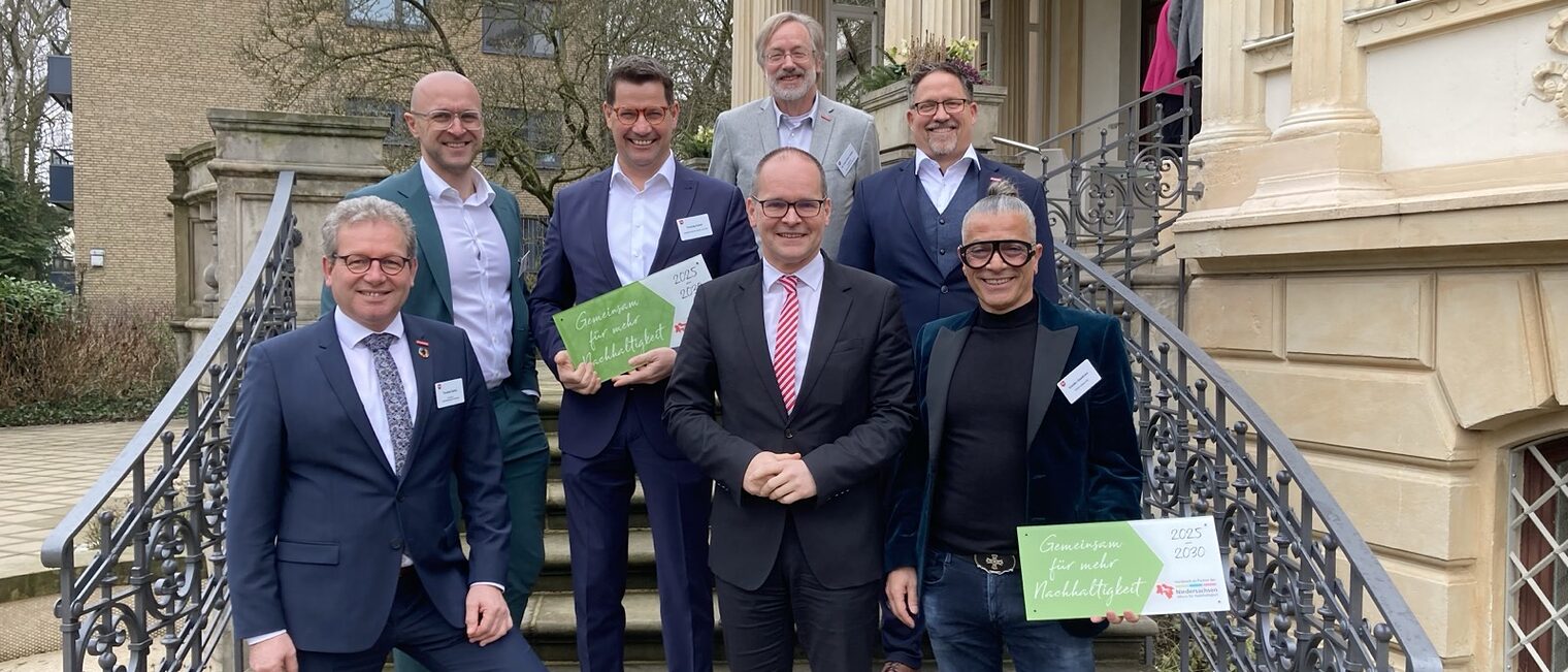 Die ausgezeichneten Betriebe mit Minister und Handwerkskammerpräsident und weiteren Personen stehen auf einer Treppe des Gästehauses der niedersächsischen Landesregierung.