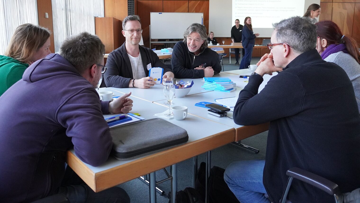 Gruppe von Männern und Frauen am Tisch in der Diskussion.