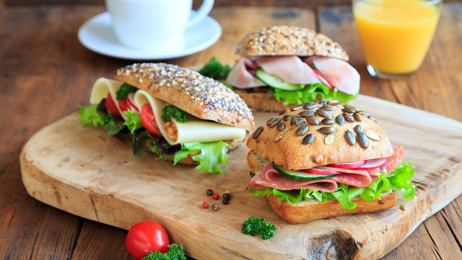 Frühstück mit belegten Brötchen, Tasse Kaffee und Orangensaft