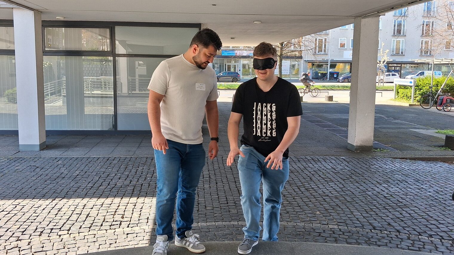 Ein Geselle lotst einen anderen mit verbundenen Augen drei Treppenstufen hoch.