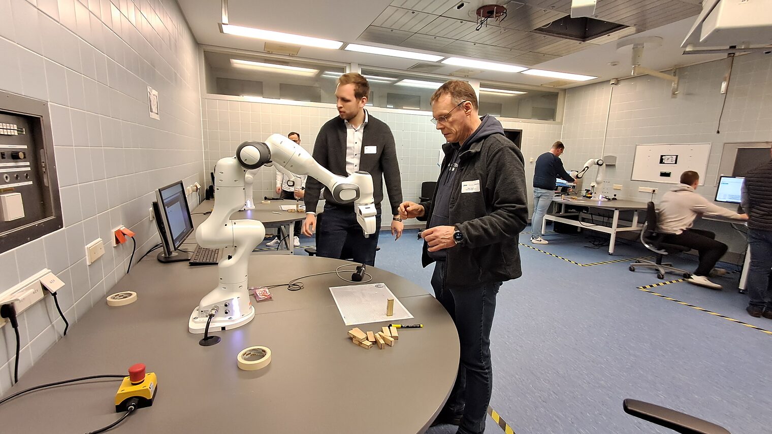 Zwei Männer betrachten Roboter auf einem Tisch