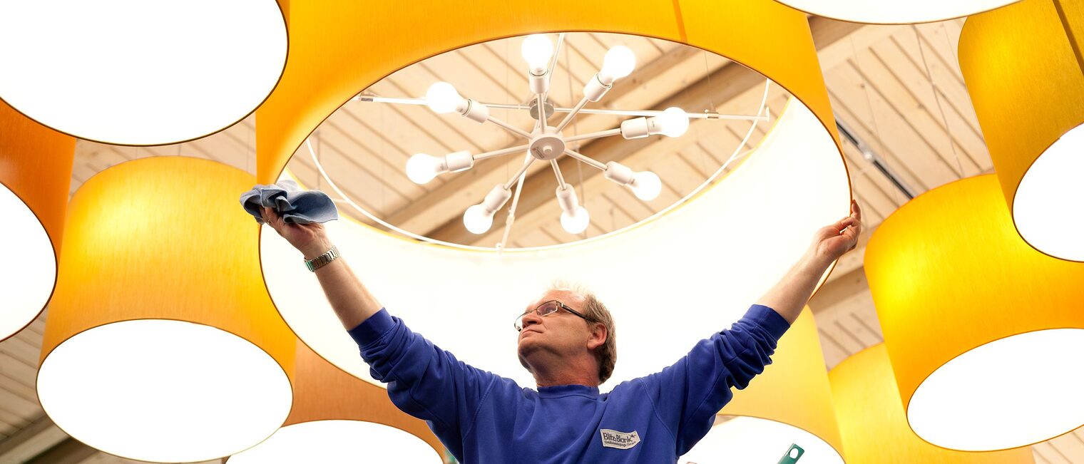 Gebäudereiniger reinigt Deckenlampe.