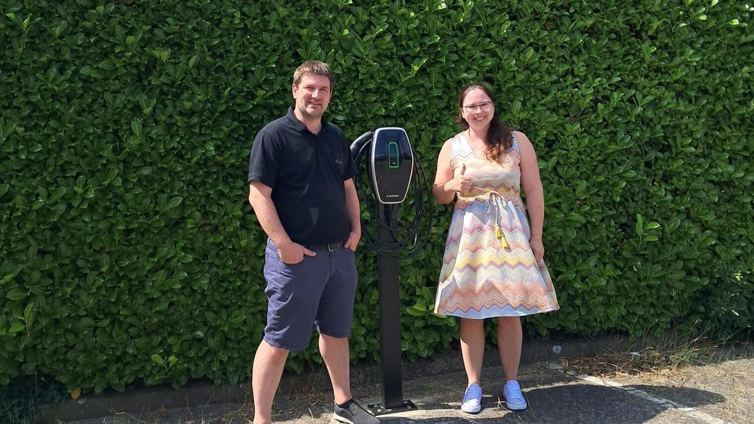 Amadeus Bürgel von der Bürgel GmbH und mehrWERT-Beraterin Ann-Katrin Buchholz nach dem Erstberatungsgespräch vor seiner E-Ladesäule.