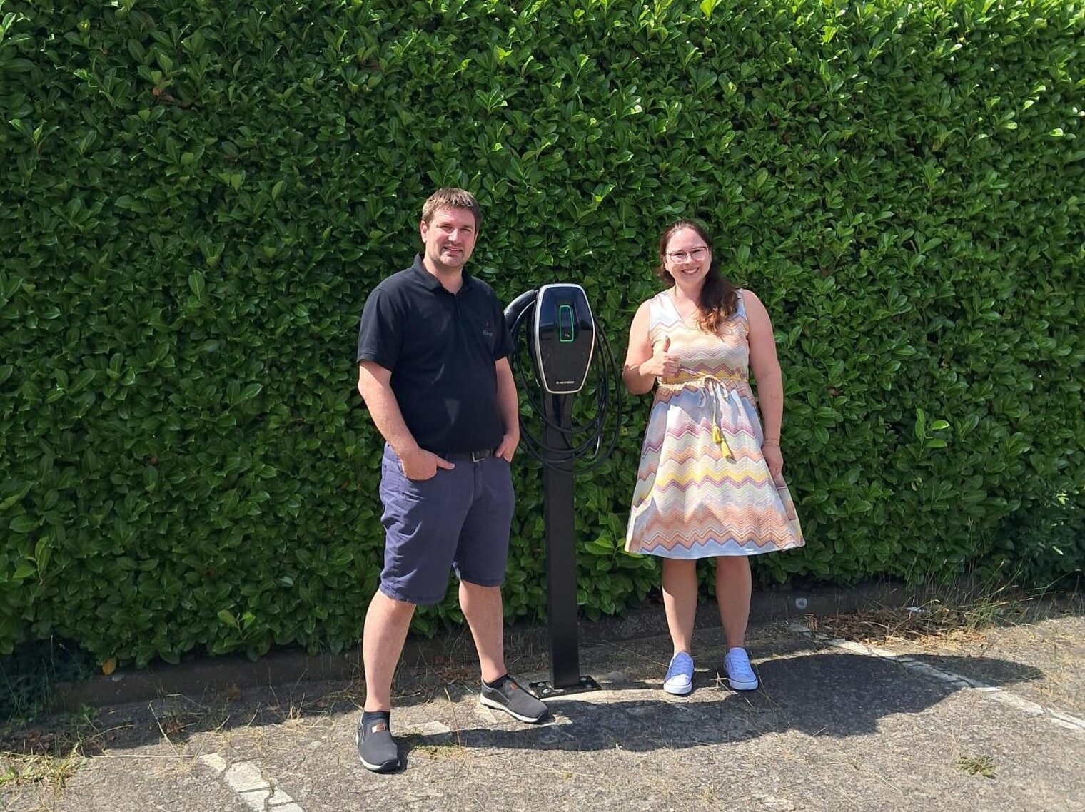 Amadeus Bürgel von der Bürgel GmbH und mehrWERT-Beraterin Ann-Katrin Buchholz nach dem Erstberatungsgespräch vor seiner E-Ladesäule.